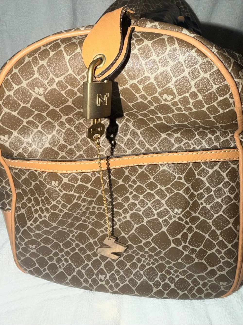 Nina Ricci Brown Patterned Duffel with Tan Trim. Has lock and key.